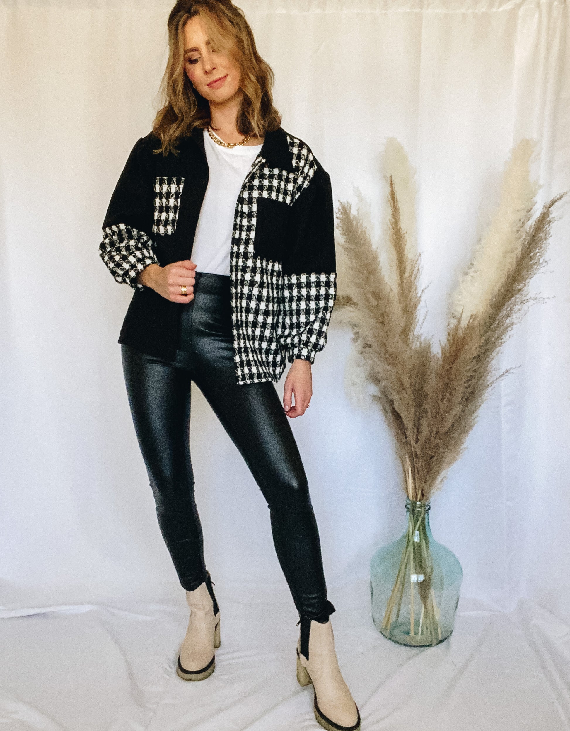 Two-tone colorblock houndstooth and black jacket with breast pockets and puff sleeve details with faux leather leggings and tan chunky heel boots